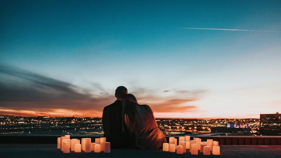 A couple look over city lights at dusk