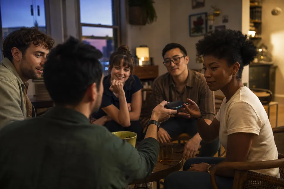 Friends discreetly passing a phone for private role reveals