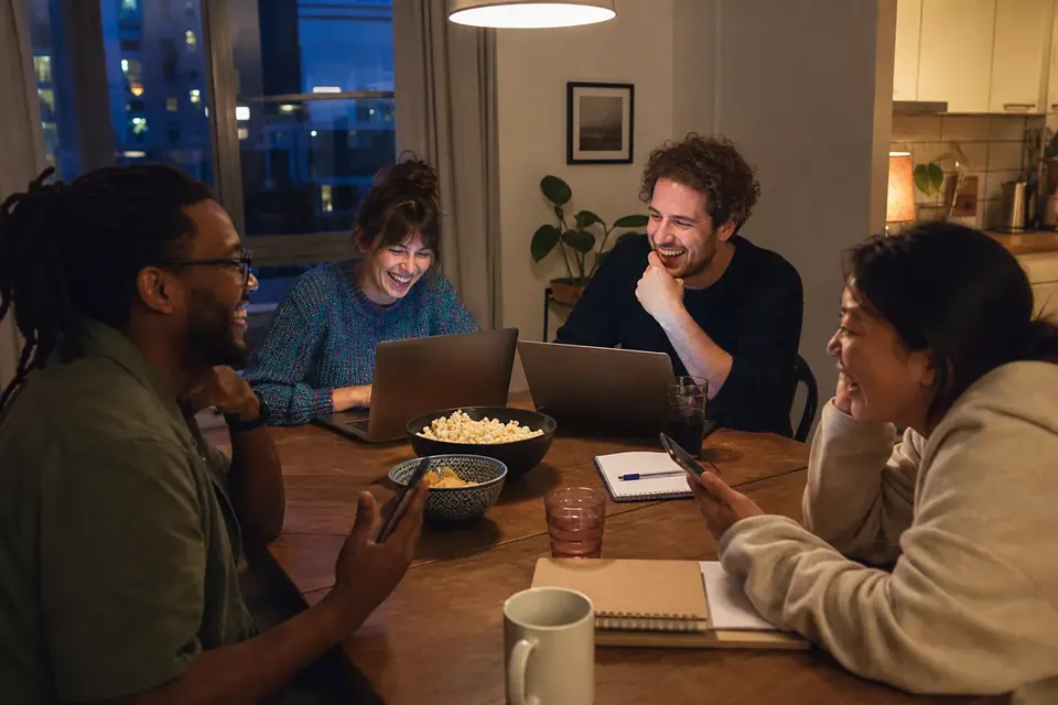 Friends using laptops and sketchpads for an online drawing game
